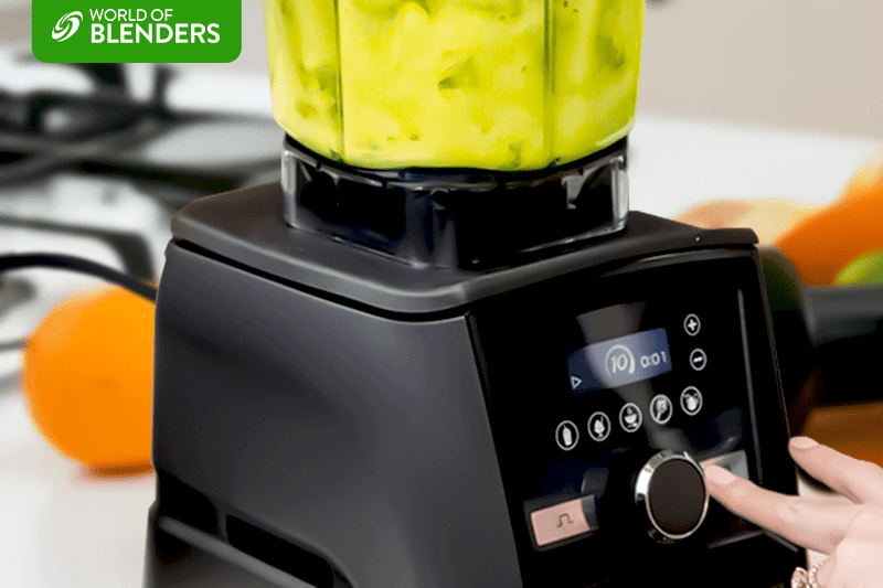 A woman is pressing the button on a blender.