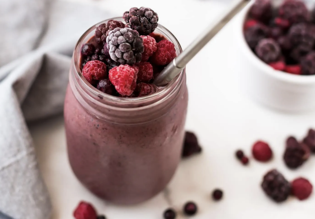 mixed berry smoothie topped with mixed berries in a glass jar