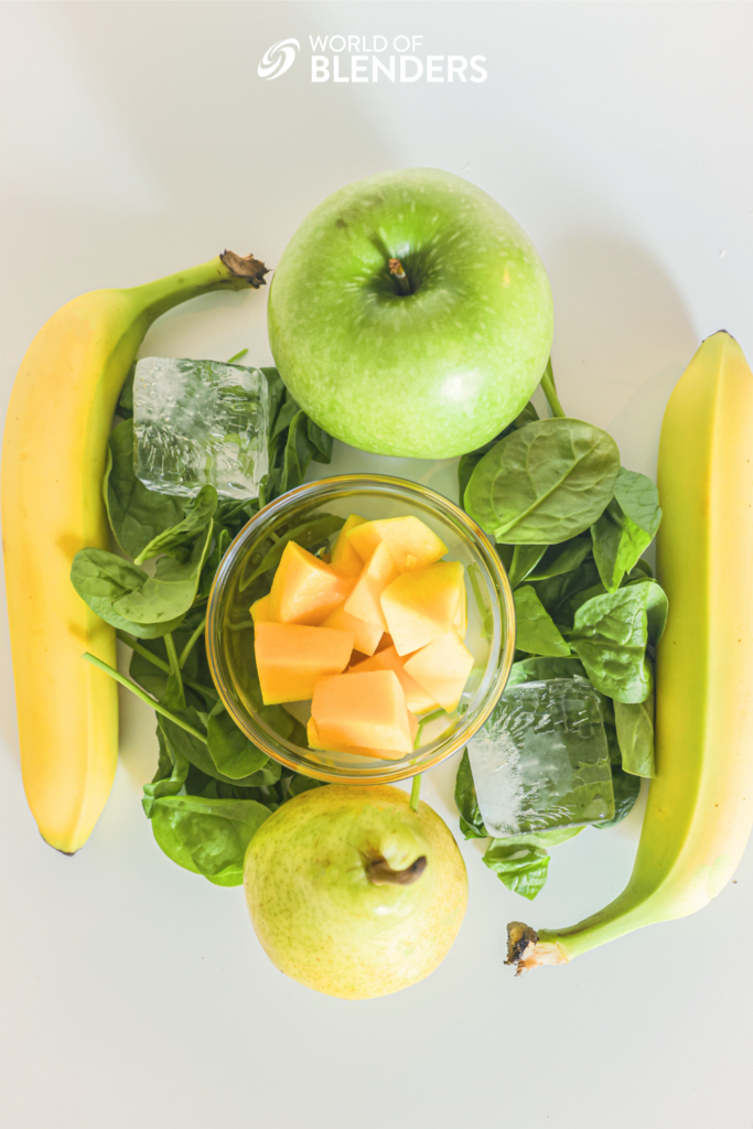 apple banana mango pear spinach and ice displayed to show ingredients in this smoothie