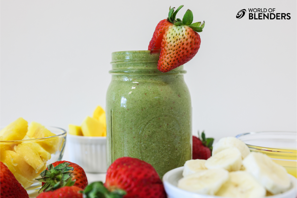 tropical green smoothie with fruit surrounding it