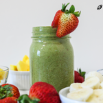 tropical green smoothie with fruit surrounding it