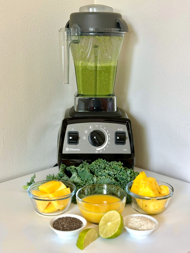 healthy mango kale smoothie in a vitamix blender with ingredients in front